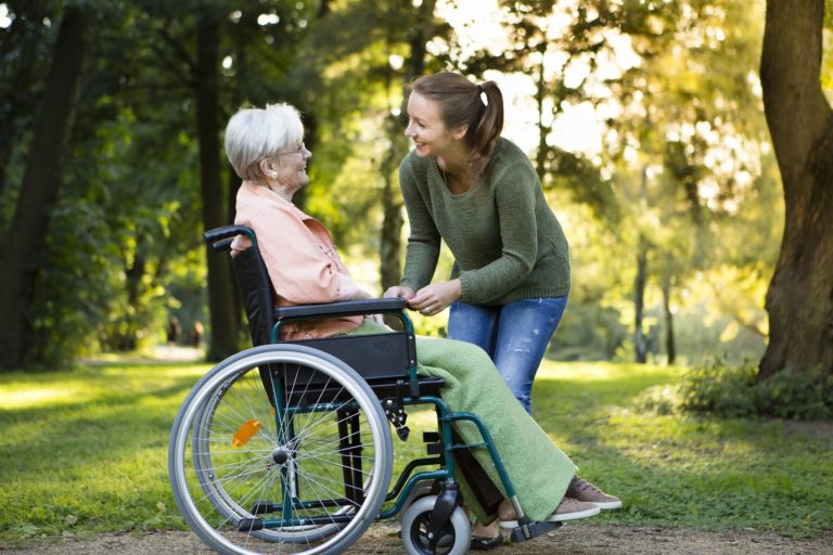 Frau betreut ältere Frau im Rollstuhl